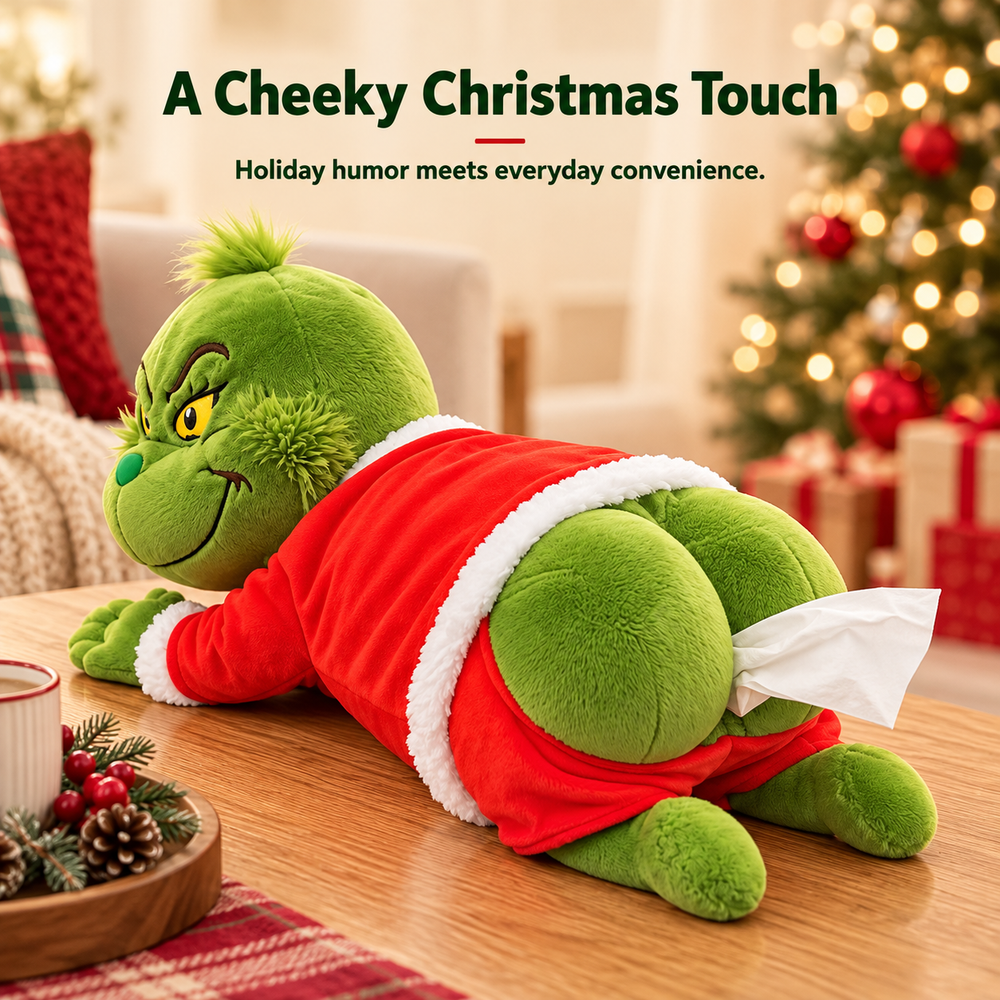 Full lifestyle view of the green Grinch-inspired plush tissue holder wearing a red Santa outfit on a festive table